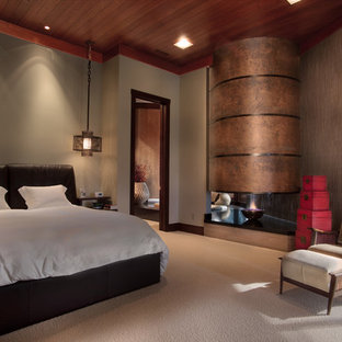 Esempio di una camera matrimoniale etnica di medie dimensioni con pareti beige, moquette, camino bifacciale, cornice del camino in metallo e pavimento beige