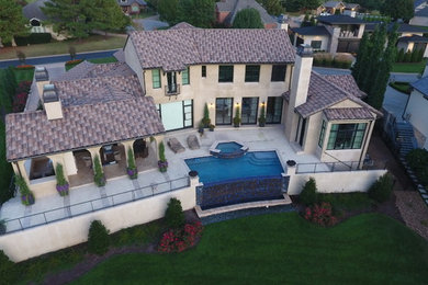 Photo of a large mediterranean two-storey stucco beige house exterior in Other with a hip roof and a tile roof.