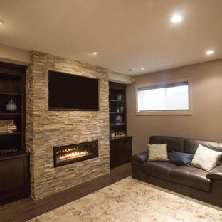 This is an example of a medium sized traditional fully buried basement in Edmonton with green walls, concrete flooring, a stone fireplace surround and a ribbon fireplace.