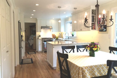 Eat-in kitchen - mid-sized traditional l-shaped medium tone wood floor and brown floor eat-in kitchen idea in Seattle with shaker cabinets, white cabinets, granite countertops, stainless steel appliances and an island