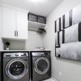 Photo of a small contemporary single-wall separated utility room in Other with flat-panel cabinets, white cabinets, laminate countertops, grey walls, porcelain flooring and a side by side washer and dryer.