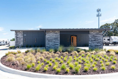 Ejemplo de fachada gris y gris moderna grande de una planta con revestimiento de estuco, tejado de un solo tendido y tejado de metal