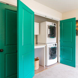 This is an example of a medium sized traditional laundry cupboard in Seattle with beige walls, carpet and a stacked washer and dryer.