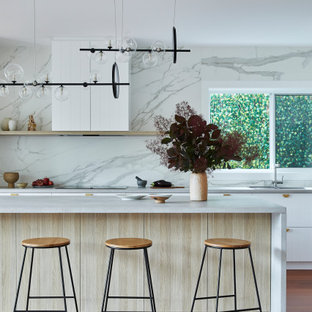 Photo of a large contemporary l-shaped eat-in kitchen in Sydney with a drop-in sink, shaker cabinets, white cabinets, quartz benchtops, white splashback, porcelain splashback, black appliances, dark hardwood floors, with island, brown floor and grey benchtop.