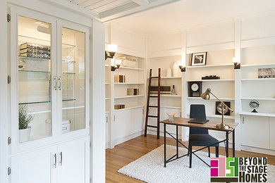 Example of a transitional freestanding desk light wood floor home office design in Other with white walls