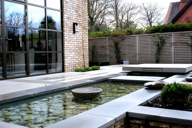 Medium sized contemporary back formal full sun garden in Cheshire with natural stone paving.