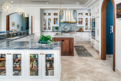 Inspiration for an expansive transitional l-shaped eat-in kitchen in Other with an undermount sink, raised-panel cabinets, white cabinets, quartzite benchtops, blue splashback, glass tile splashback, stainless steel appliances, terrazzo floors, with island and multi-coloured benchtop.