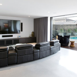 Example of a large trendy open concept concrete floor home theater design in Newcastle - Maitland with white walls