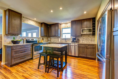 Mid-sized transitional medium tone wood floor kitchen photo in Birmingham with an undermount sink, flat-panel cabinets, gray cabinets, granite countertops, white backsplash, stone tile backsplash, stainless steel appliances and an island