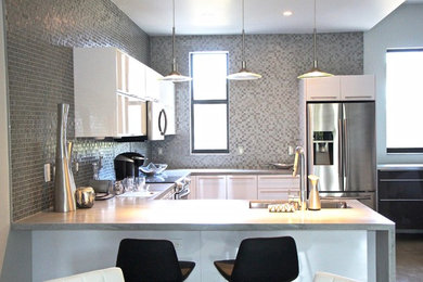 Example of a mid-sized trendy u-shaped concrete floor and beige floor open concept kitchen design in Miami with an undermount sink, flat-panel cabinets, white cabinets, concrete countertops, brown backsplash, mosaic tile backsplash, stainless steel appliances, a peninsula and beige countertops