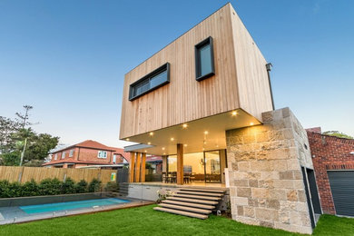 Design ideas for a mid-sized contemporary two-storey beige house exterior in Sydney with wood siding and a metal roof.