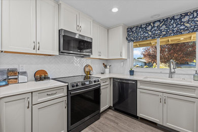 Inspiration for a small u-shaped brown floor eat-in kitchen remodel in Boise with shaker cabinets, white cabinets, quartz countertops, white backsplash, porcelain backsplash and stainless steel appliances