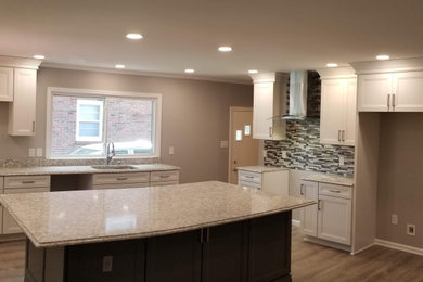 Kitchen pantry - large modern l-shaped light wood floor, brown floor and vaulted ceiling kitchen pantry idea in Louisville with an undermount sink, recessed-panel cabinets, white cabinets, quartz countertops, multicolored backsplash, matchstick tile backsplash, stainless steel appliances, an island and gray countertops