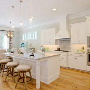 Mid-sized mediterranean kitchen pantry ideas - Kitchen pantry - mid-sized mediterranean l-shaped light wood floor kitchen pantry idea in Jacksonville with an undermount sink, raised-panel cabinets, white cabinets, quartz countertops, white backsplash, ceramic backsplash, stainless steel appliances and an island