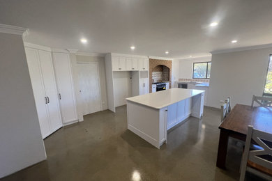 Photo of a large kitchen in Other with shaker cabinets, white cabinets, quartz benchtops, concrete floors and with island.