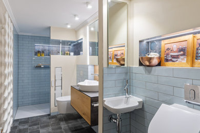 Mittelgroßes Modernes Duschbad mit flächenbündigen Schrankfronten, hellen Holzschränken, bodengleicher Dusche, Wandtoilette, braunen Fliesen, Keramikfliesen, beiger Wandfarbe, Aufsatzwaschbecken, offener Dusche und schwarzer Waschtischplatte