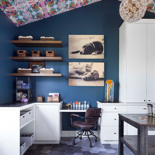 This is an example of a large eclectic craft room in Denver with blue walls, ceramic floors, no fireplace, a built-in desk and grey floor.