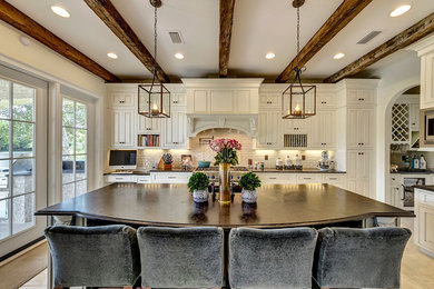 Inspiration for a large transitional l-shaped eat-in kitchen in New Orleans with raised-panel cabinets, white cabinets, subway tile splashback, with island, an undermount sink, granite benchtops, beige splashback, stainless steel appliances and porcelain floors.