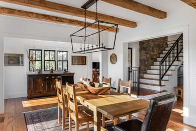 Example of a large cottage medium tone wood floor, brown floor and exposed beam dining room design in Columbus with white walls