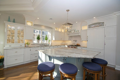 Eat-in kitchen - mid-sized traditional l-shaped medium tone wood floor eat-in kitchen idea in Newark with an undermount sink, recessed-panel cabinets, white cabinets, marble countertops, white backsplash, subway tile backsplash, paneled appliances and an island