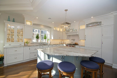 This is an example of a medium sized traditional l-shaped kitchen/diner in Newark with a submerged sink, recessed-panel cabinets, white cabinets, marble worktops, white splashback, metro tiled splashback, integrated appliances, medium hardwood flooring and an island.