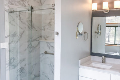 Photo of a large modern master bathroom in Raleigh with flat-panel cabinets, white cabinets, a freestanding tub, an alcove shower, a one-piece toilet, black and white tile, porcelain tile, grey walls, porcelain floors, an undermount sink, engineered quartz benchtops, white floor, a sliding shower screen and white benchtops.