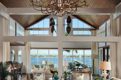 Example of a large island style open concept medium tone wood floor and brown floor living room design in Miami with white walls and no fireplace