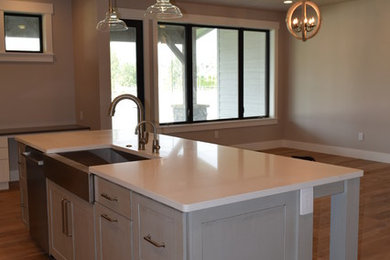 Open concept kitchen - transitional l-shaped medium tone wood floor open concept kitchen idea in Other with a farmhouse sink, shaker cabinets, white cabinets, quartz countertops, gray backsplash, subway tile backsplash, stainless steel appliances and an island