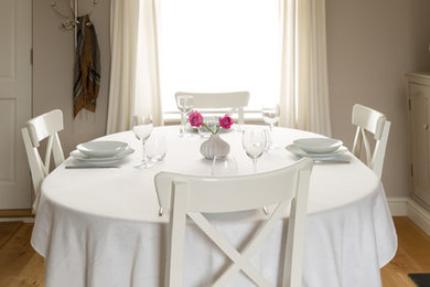 Photo of a medium sized open plan dining room in Cambridgeshire with grey walls, light hardwood flooring, a wooden fireplace surround and a standard fireplace.
