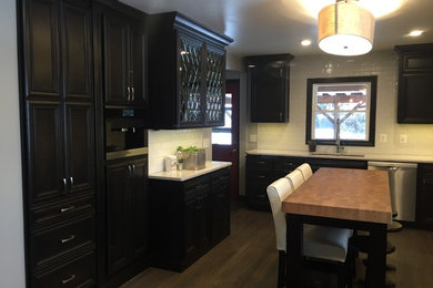 Inspiration for a mid-sized transitional l-shaped eat-in kitchen in Wichita with an undermount sink, recessed-panel cabinets, dark wood cabinets, quartz benchtops, white splashback, subway tile splashback, stainless steel appliances, medium hardwood floors and with island.