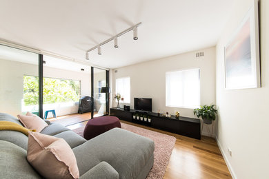Photo of a modern living room in Sydney with white walls and medium hardwood floors.