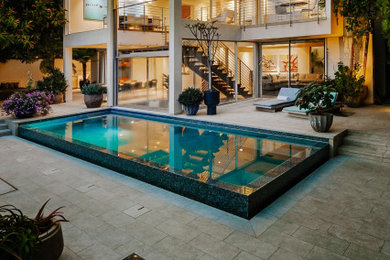 Large modern backyard rectangular infinity pool in Los Angeles with a hot tub.