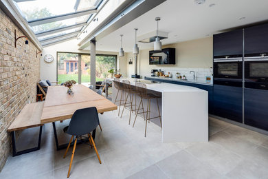 Mid-sized contemporary single-wall kitchen in London with an undermount sink, flat-panel cabinets, blue cabinets, stainless steel appliances, slate floors, with island and grey floor.