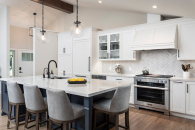 Inspiration for a large transitional medium tone wood floor, multicolored floor and vaulted ceiling eat-in kitchen remodel in Other with an integrated sink, shaker cabinets, white cabinets, quartz countertops, white backsplash, brick backsplash, paneled appliances, an island and white countertops