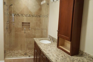 Alcove shower - mid-sized traditional 3/4 beige tile and porcelain tile porcelain tile alcove shower idea in Los Angeles with beaded inset cabinets, medium tone wood cabinets, beige walls, an undermount sink and granite countertops