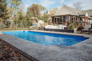 Imagen de piscina contemporánea de tamaño medio rectangular en patio trasero con paisajismo de piscina y suelo de hormigón estampado