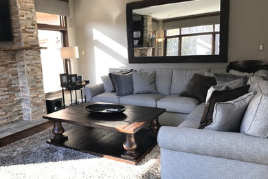 Photo of a mid-sized country open concept family room in Detroit with beige walls, dark hardwood floors, a standard fireplace, a stone fireplace surround, a wall-mounted tv and brown floor.