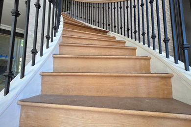 Example of a large tuscan wooden curved mixed material railing staircase design in New York with wooden risers