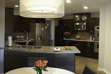 Eat-in kitchen - mid-sized contemporary u-shaped vinyl floor and brown floor eat-in kitchen idea in Dallas with an undermount sink, shaker cabinets, dark wood cabinets, granite countertops, brown backsplash, glass tile backsplash, stainless steel appliances and a peninsula