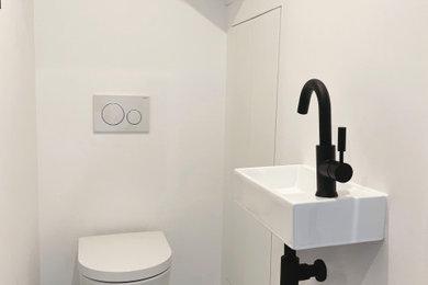 Cette image montre un WC suspendu design avec un placard à porte affleurante, un mur blanc, un sol en carrelage de céramique, un lavabo suspendu, un sol multicolore et meuble-lavabo encastré.