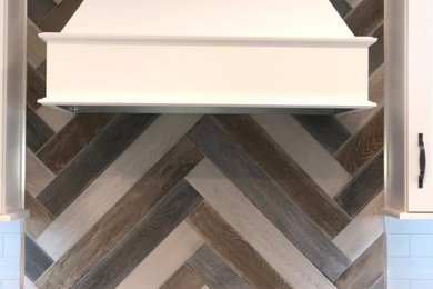 Example of a mid-sized country l-shaped medium tone wood floor and brown floor eat-in kitchen design in St Louis with a single-bowl sink, shaker cabinets, white cabinets, quartz countertops, gray backsplash, subway tile backsplash, stainless steel appliances, an island and white countertops