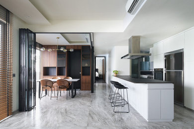 Contemporary galley kitchen with flat-panel cabinets, white cabinets, stainless steel appliances, with island, grey floor and black benchtop.