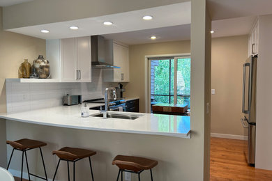 Inspiration for a mid-sized modern u-shaped medium tone wood floor enclosed kitchen remodel in Other with an undermount sink, recessed-panel cabinets, quartz countertops, white backsplash, ceramic backsplash, stainless steel appliances, an island and white countertops