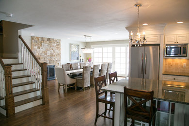 Mid-sized elegant medium tone wood floor kitchen/dining room combo photo in Denver with white walls, a standard fireplace and a stone fireplace