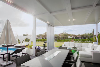 Large modern backyard patio in Miami with concrete pavers and a pergola.