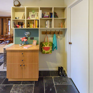 This is an example of a small modern home office and library in Melbourne with slate flooring, a built-in desk and black floors.