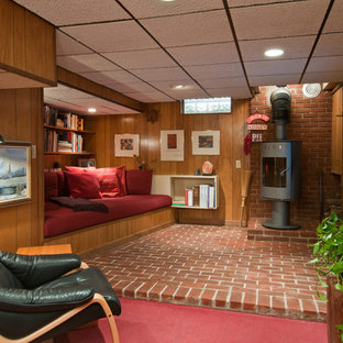 This is an example of a small retro look-out basement in Detroit with a wood burning stove, brick flooring and red floors.