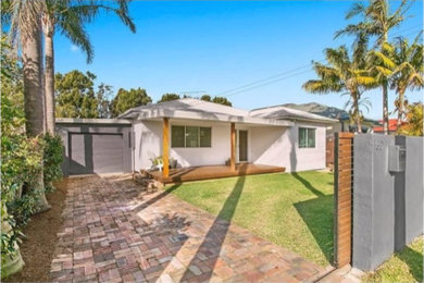 Example of a mid-sized minimalist gray one-story brick exterior home design in Wollongong with a hip roof