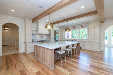 Elegant u-shaped light wood floor and wood ceiling open concept kitchen photo in Other with a farmhouse sink, beaded inset cabinets, white cabinets, marble countertops, ceramic backsplash, paneled appliances and an island