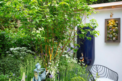 This is an example of a small contemporary courtyard full sun garden for summer in London with a potted garden and decking.